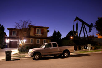 In Signal Hill, California, an oil pump jack stands idle near homes, in February 2023. California law S.B. 1137, which required a safety buffer zone of 3,200 feet around homes and schools for new oil and gas drilling, was suspended after the petroleum industry last year collected enough signatures in a petition campaign to place a referendum on the 2024 general election ballot. The bill was originally signed into law by Governor Gavin Newsom last year and also banned new drilling near parks, health care facilities, prisons and businesses open to the public. Credit: Mario Tama/Getty Images.