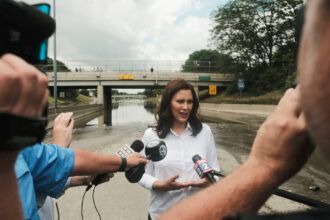 Michigan Governor Gretchen Whitmer speaks to the press on an inundated I-94 in Detroit after a weekend of heavy rains.