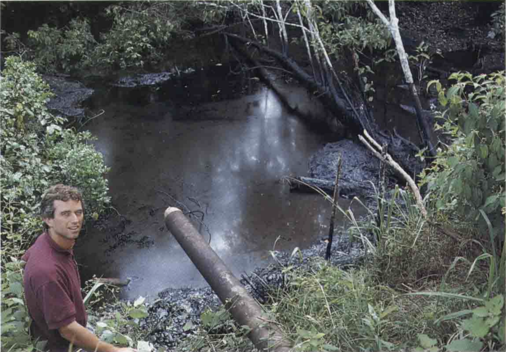 Robert F. Kennedy Jr. stands next to where drilling waste drains into a stream in July 1990. The photo was originally published in Kimerling's Amazon Crude. Credit: courtesy of Judith Kimerling